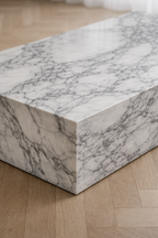 Close up of a minimal rectangular block coffee table, with white marble and delicate grey veining.