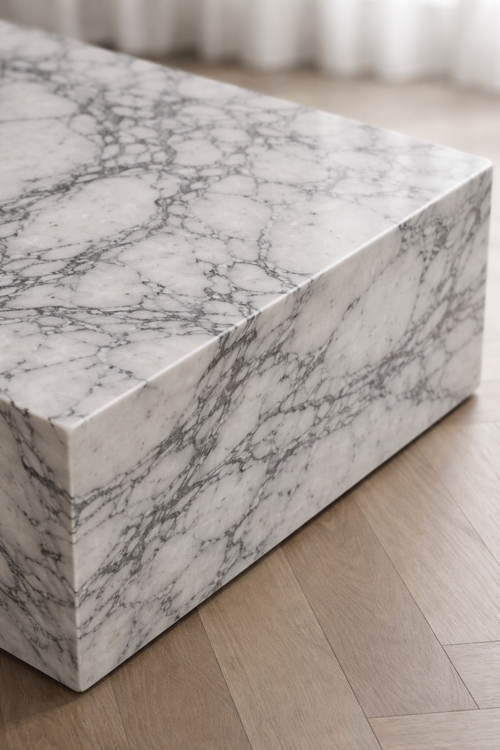 Close up of a minimal rectangular block coffee table, with white marble and delicate grey veining.