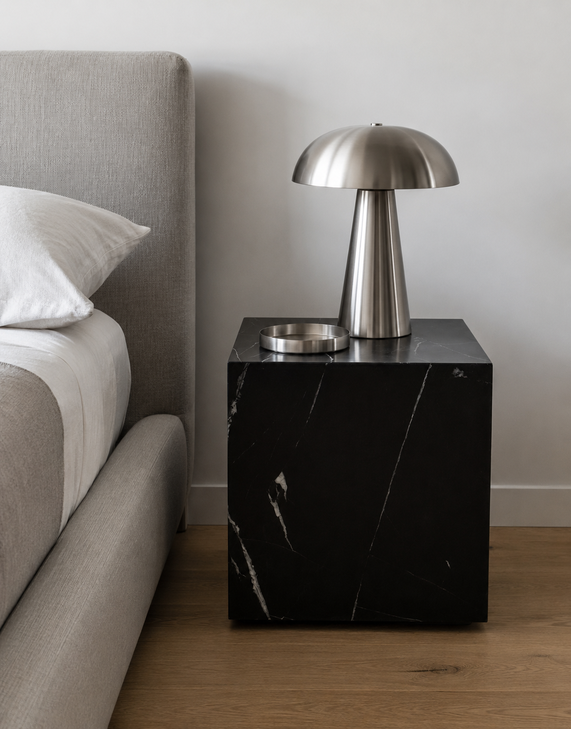 Luxury black marble with delicate white veining pattern cube side table with a metallic lamp in a modern Australian bedroom.