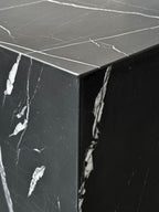 Close-up of a luxury black marble with delicate white veining pattern cube side table. Honed finish.