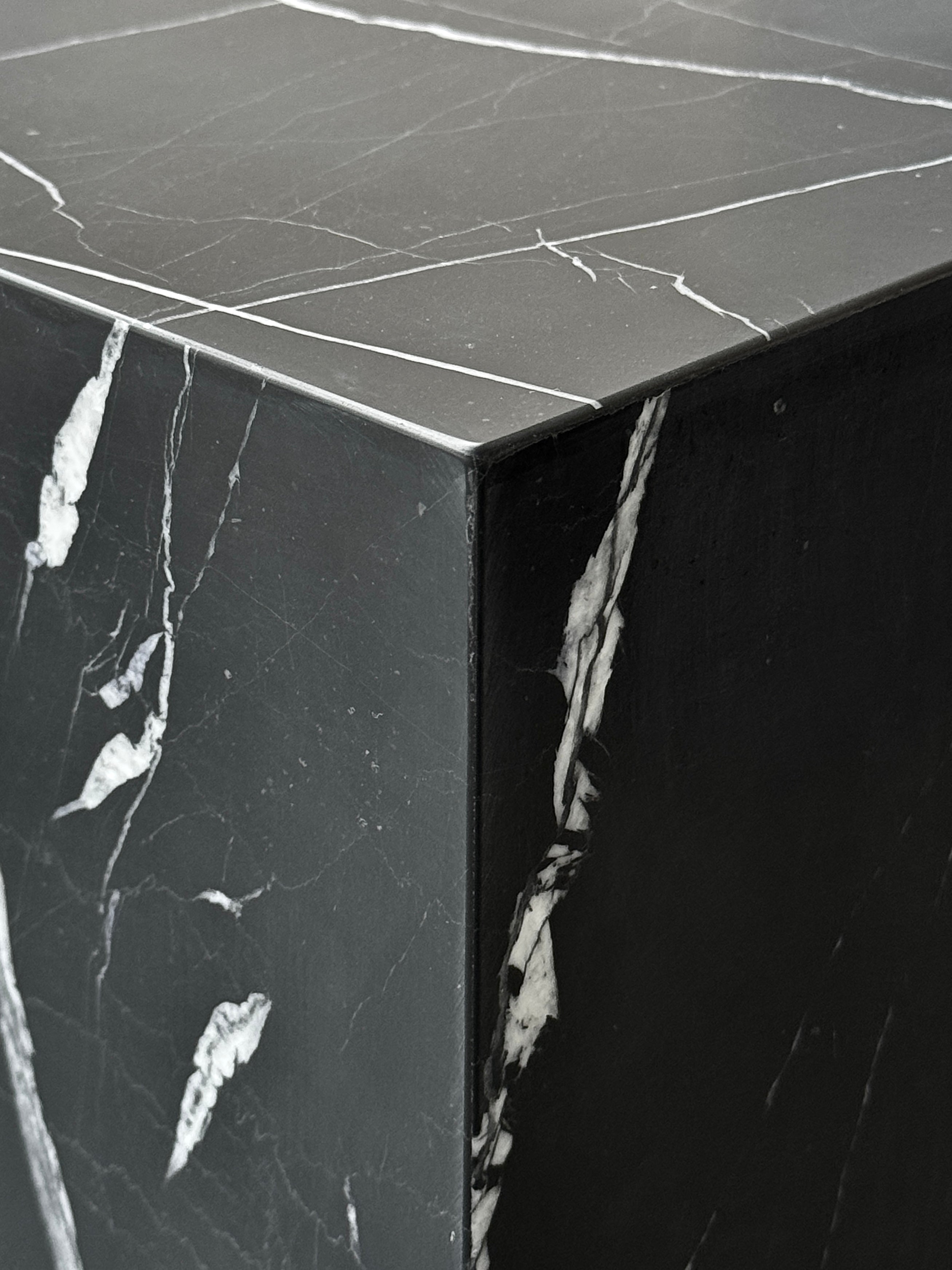 Close-up of a luxury black marble with delicate white veining pattern cube side table. Honed finish.
