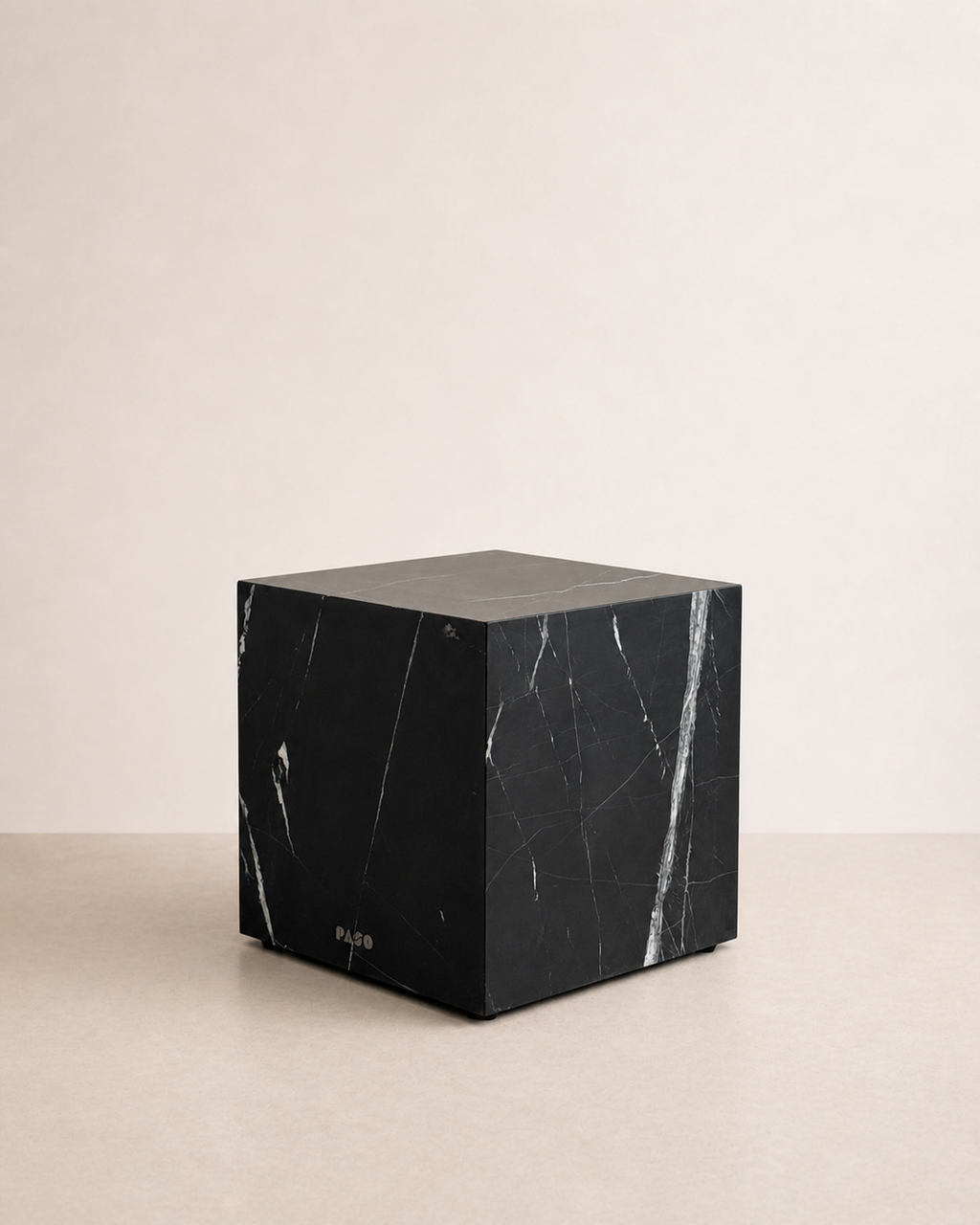 Luxury black marble with delicate white veining pattern cube side table in a off white studio background. Side view.