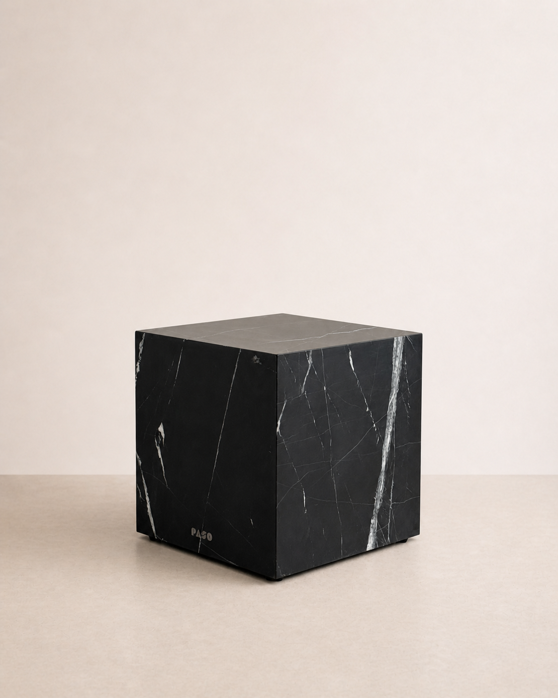Luxury black marble with delicate white veining pattern cube side table in a off white studio background. Side view.