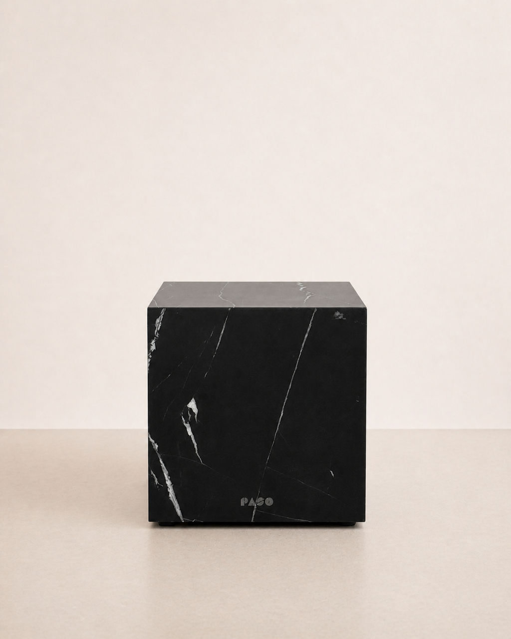 Luxury black marble with delicate white veining pattern cube side table in a off white studio background. Front view.
