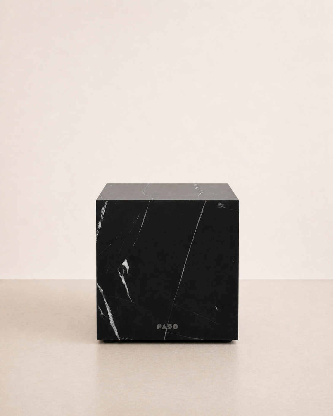 Luxury black marble with delicate white veining pattern cube side table in a off white studio background. Front view.