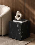 Luxury black marble with delicate white veining pattern cube side table with a book and abstract sculpture in a modern Australian living room.