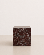 Luxury deep burgundy marble with delicate white veining pattern cube side table in a off white studio background. Front view.