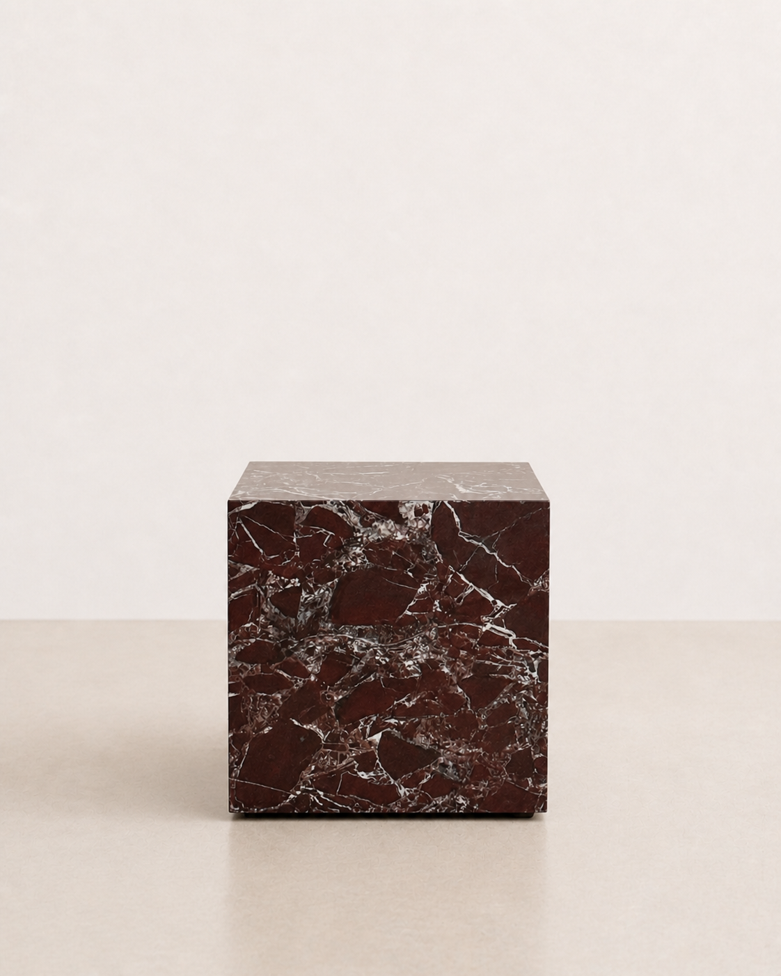 Luxury deep burgundy marble with delicate white veining pattern cube side table in a off white studio background. Front view.