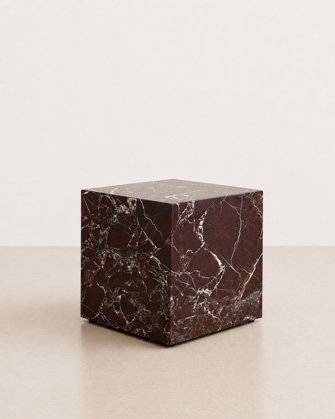 Luxury deep burgundy marble with delicate white veining pattern cube side table in a off white studio background. Side view.
