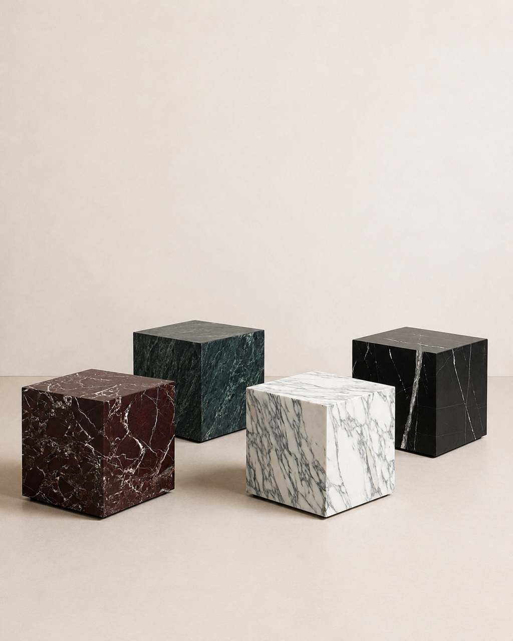 Editorial of four marble cube tables in different colors on a beige studio background