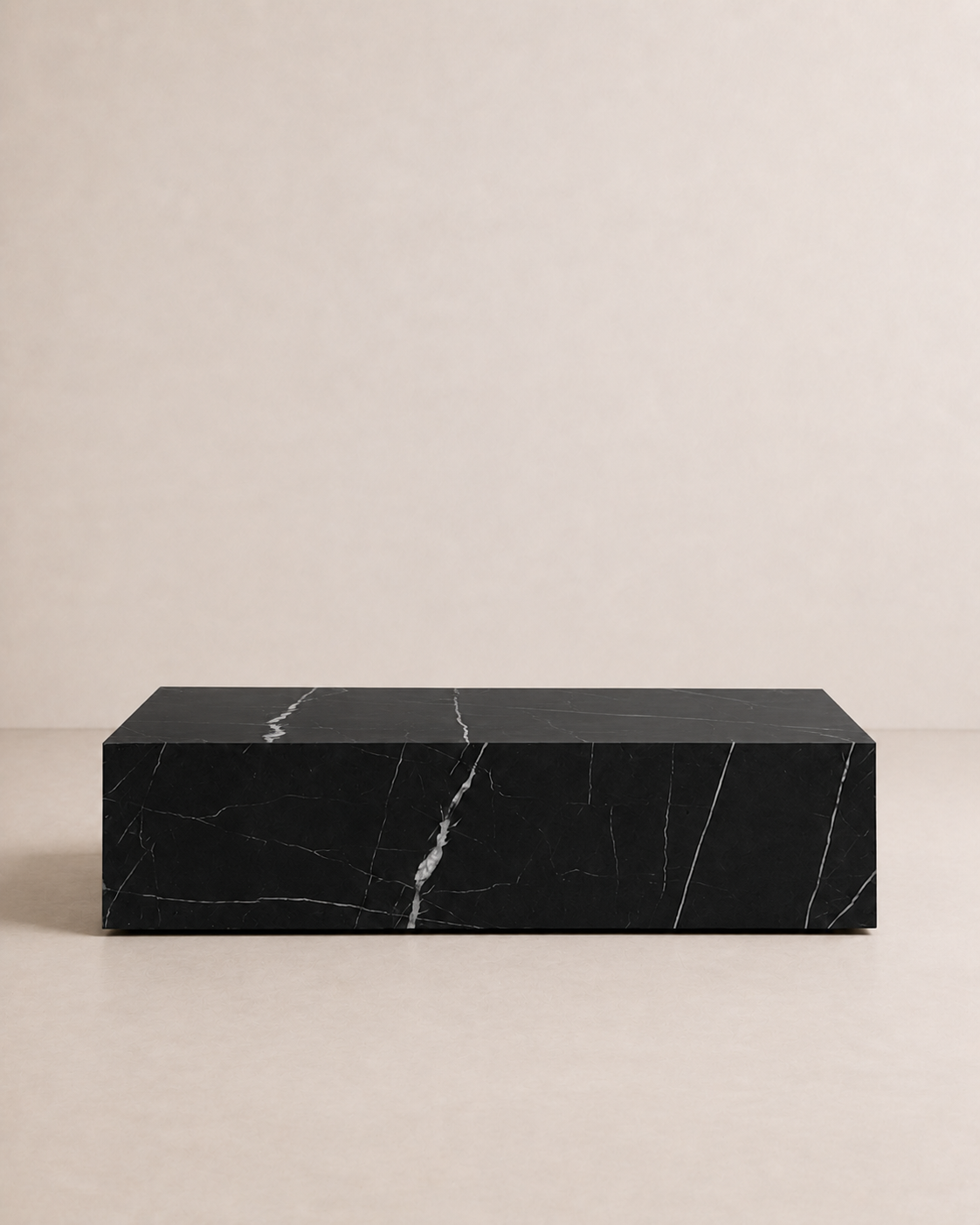 A minimal rectangular block coffee table, made of black marble and delicate white veining in an off-white studio. Front view. 