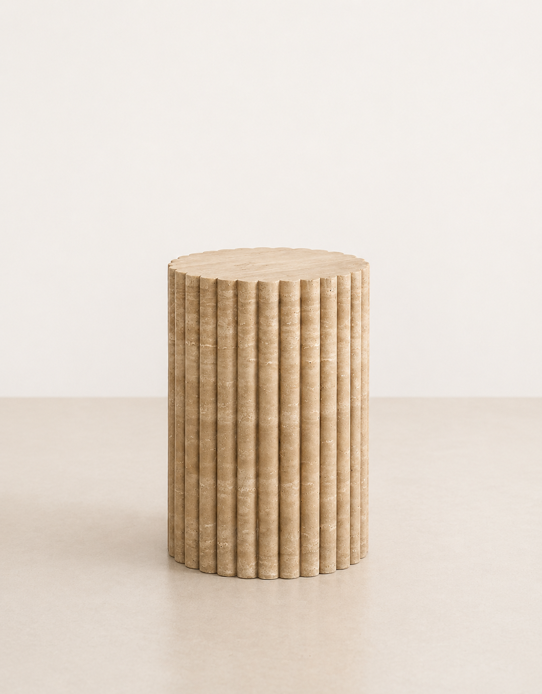 A short fluted beige travertine plinth with natural grain texture placed in a beige studio.