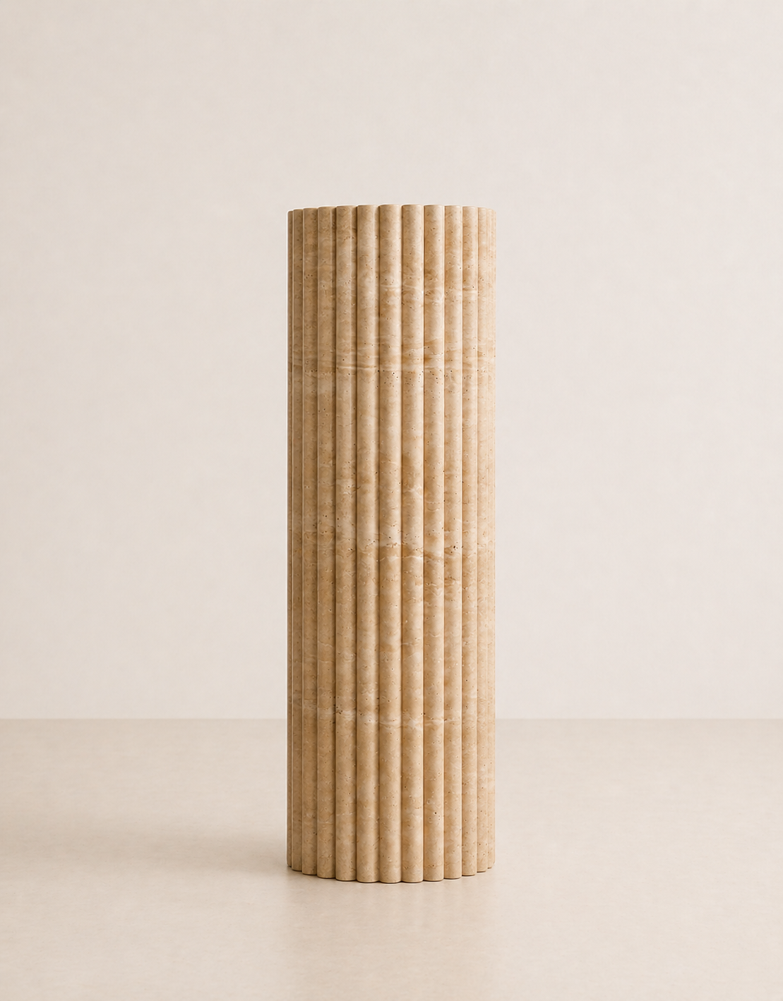 A tall fluted beige travertine plinth with natural grain texture placed in a beige studio. Front view