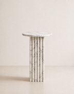 White marble side table with a ribbed cylindrical design n a beige background