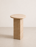 Beige travertine side table with a ribbed cylindrical design n a beige background
