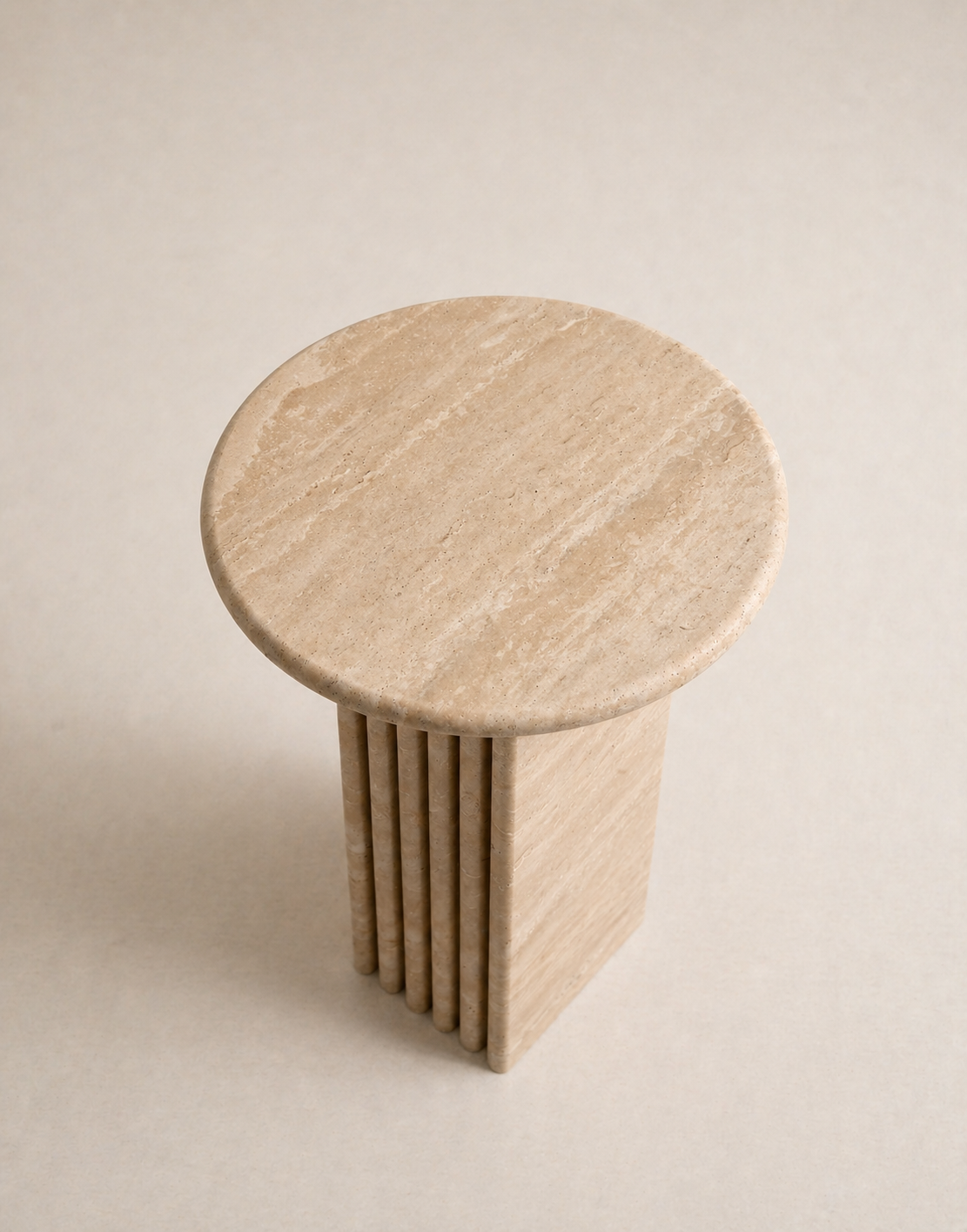 Beige travertine side table with a ribbed cylindrical design n a beige background
