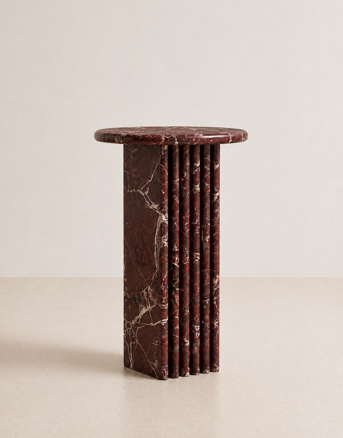 Luxury burgundy red marble side table with a ribbed cylindrical design in a beige background