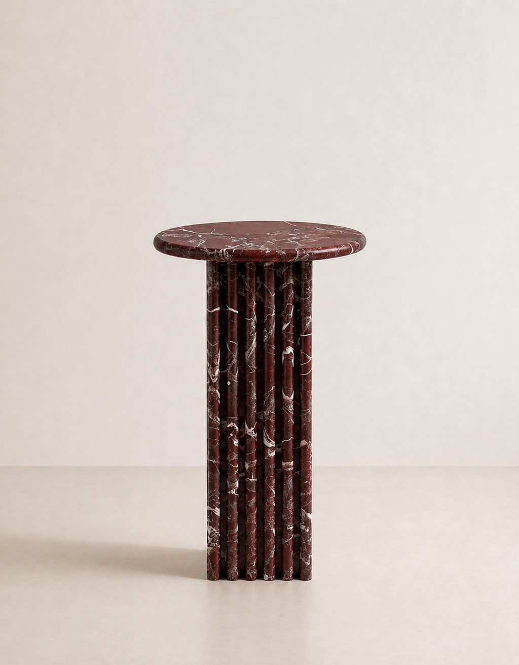 Luxury burgundy red marble side table with a ribbed cylindrical design in a beige background