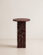 Luxury burgundy red marble side table with a ribbed cylindrical design in a beige background