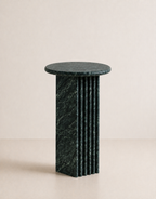 Emerald green marble side table with a ribbed cylindrical design n a beige background