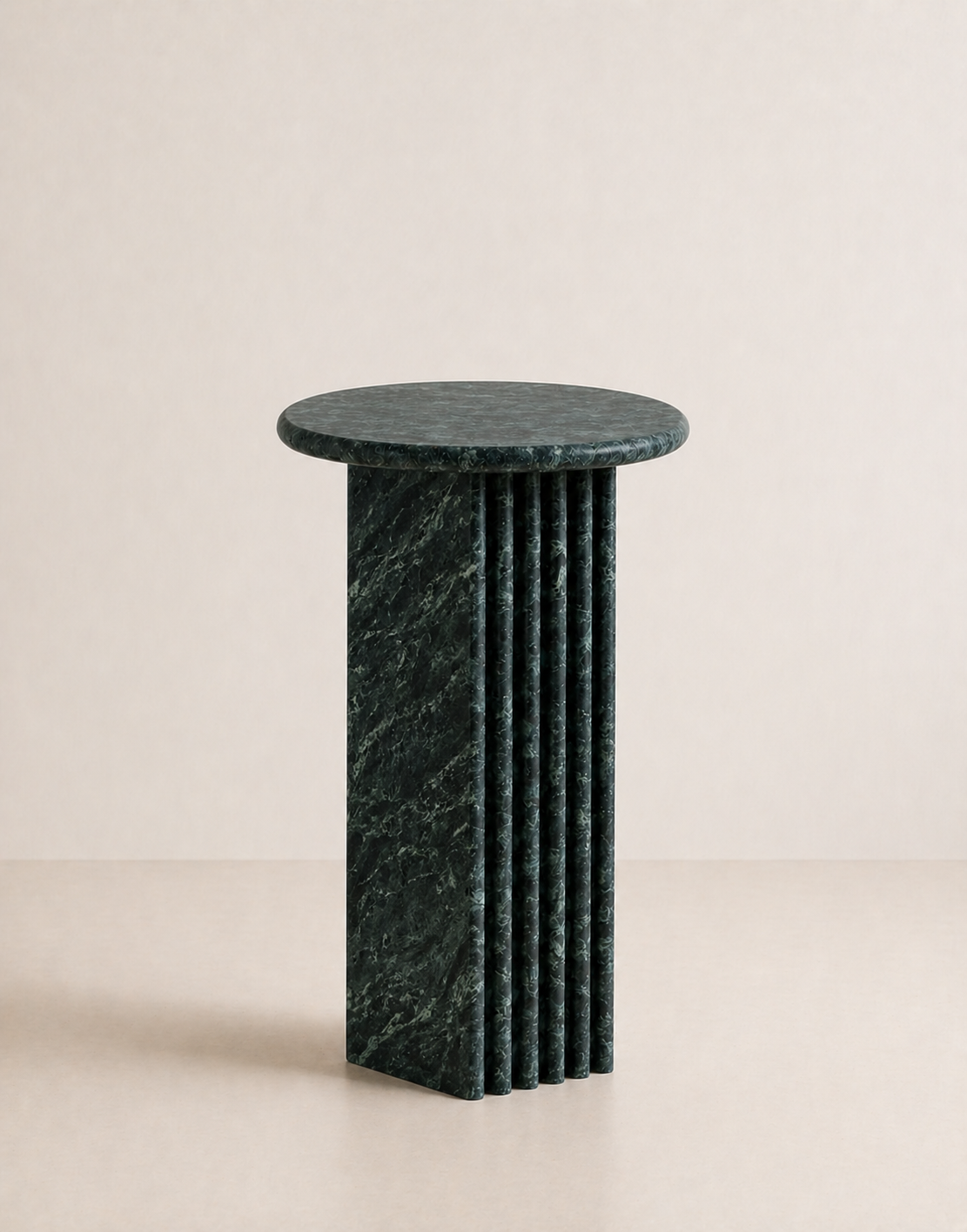Emerald green marble side table with a ribbed cylindrical design n a beige background