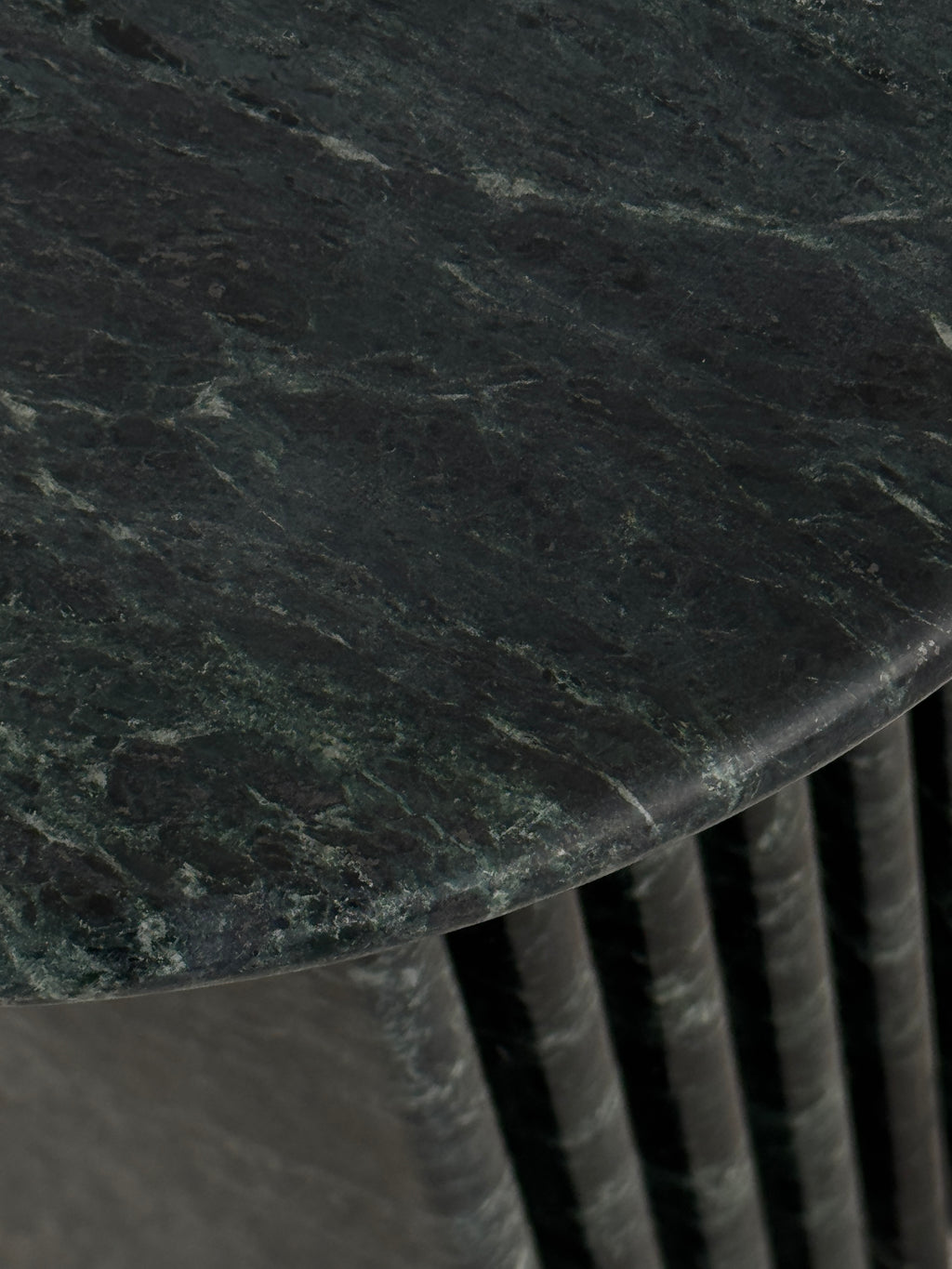 Close up of emerald green marble side table with a ribbed cylindrical design. Honed finish.