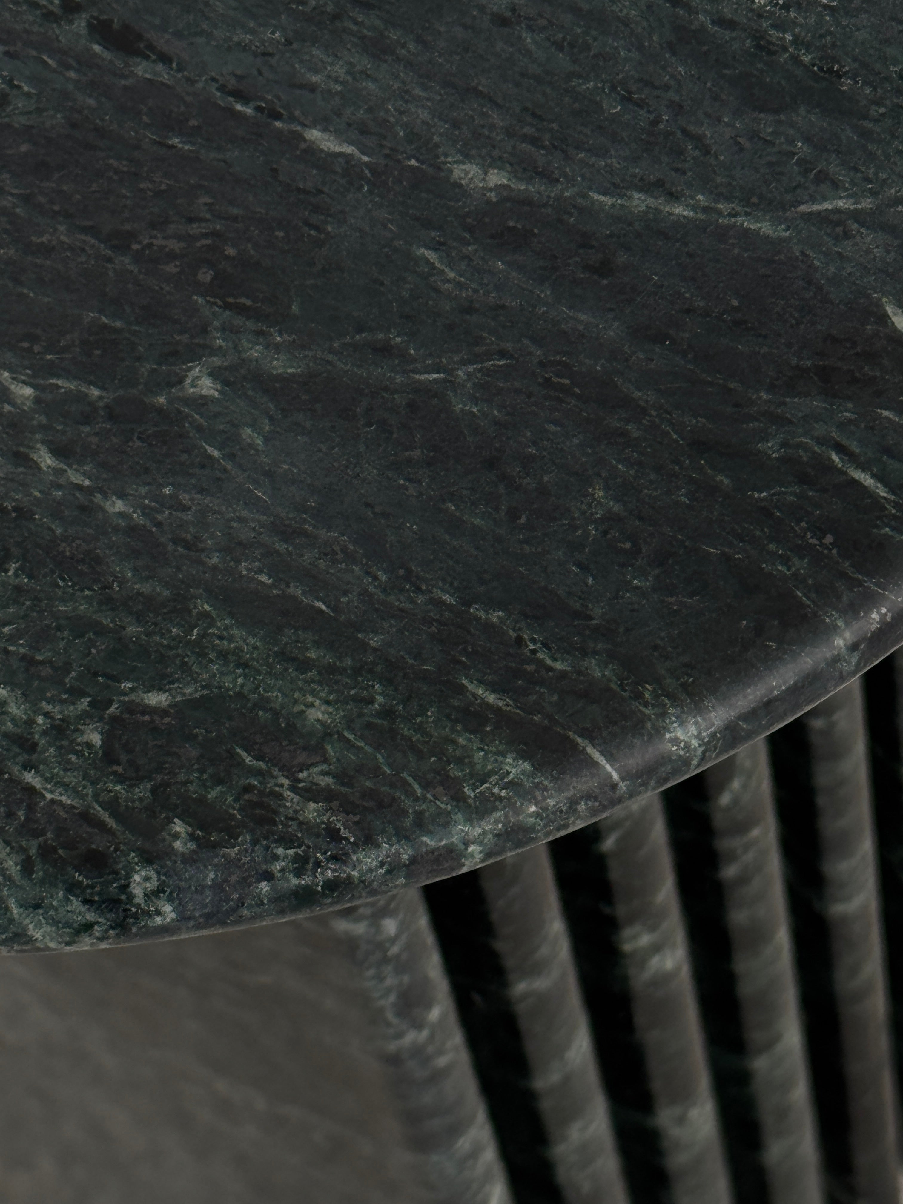 Close up of emerald green marble side table with a ribbed cylindrical design. Honed finish.