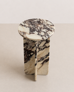 Luxury cream marble with deep violet veining pattern round side table in a off white studio background. Angled view.