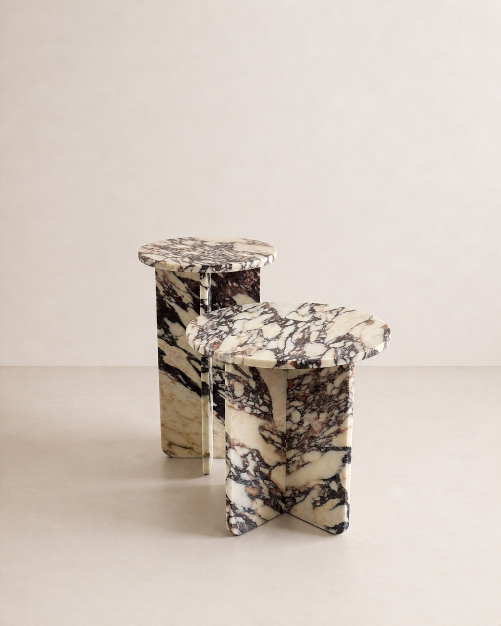 A set of two luxury cream marble with deep violet veining pattern round side tables in a off white studio background. 