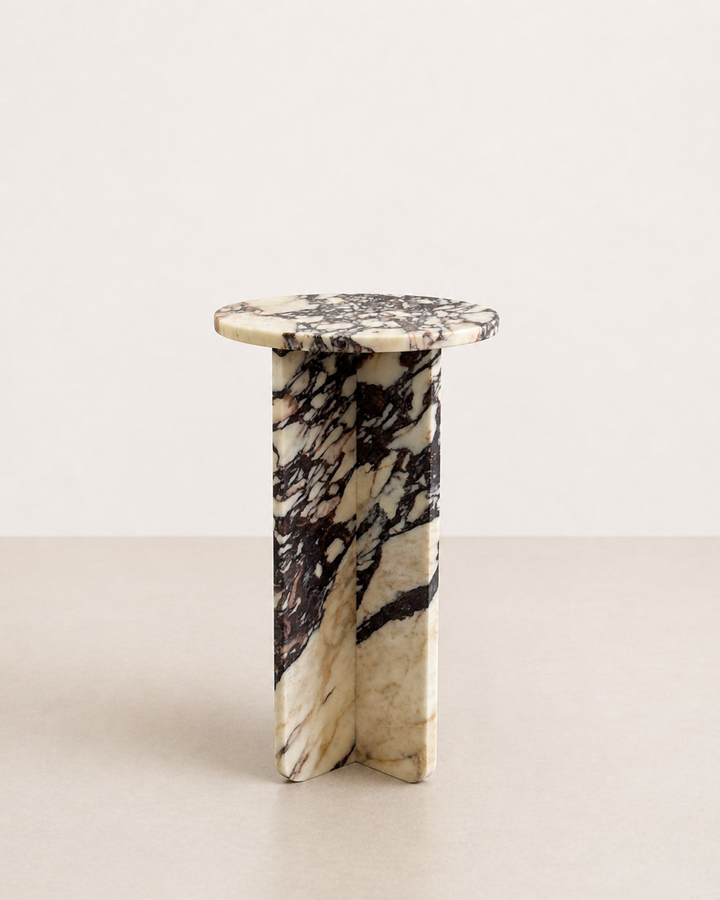 Luxury cream marble with deep violet veining pattern round side table in a off white studio background. Side view.
