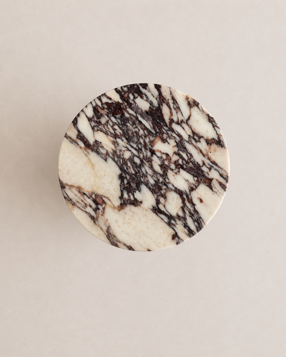 Luxury cream marble with deep violet veining pattern round side table in a off white studio background. Top view.