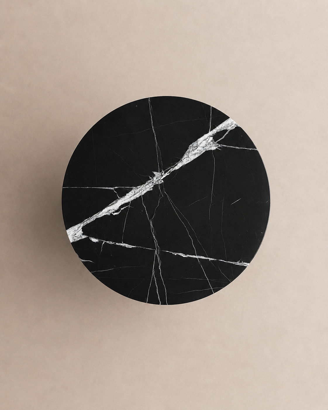 A luxury black marble with delicate white veining pattern round side table in a off white studio background. Top view.