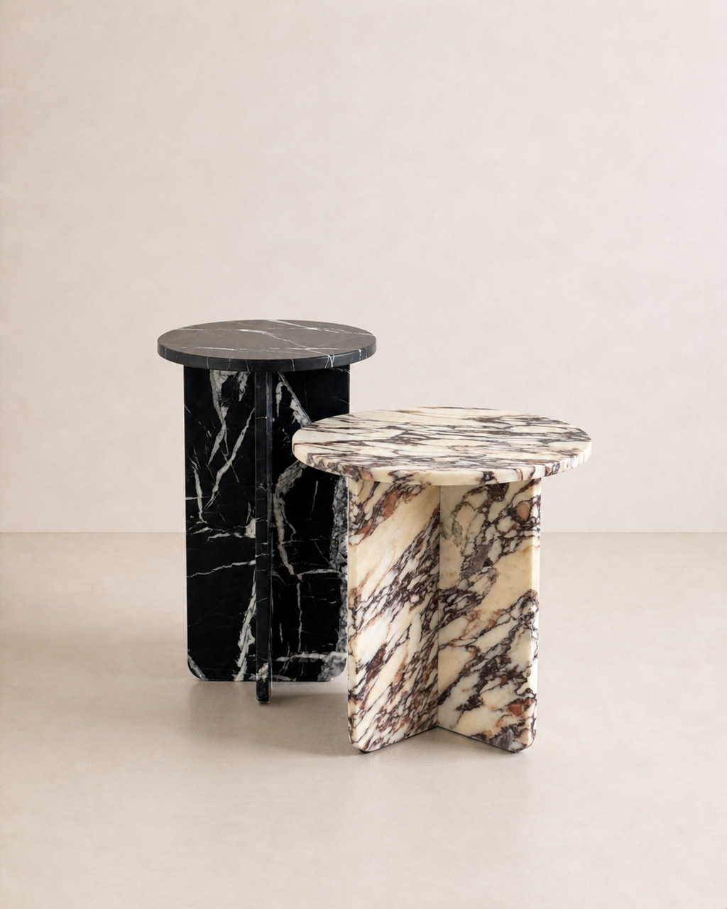 A set of two luxury black marble with delicate white veining pattern round side table in a off white studio background. Front view.